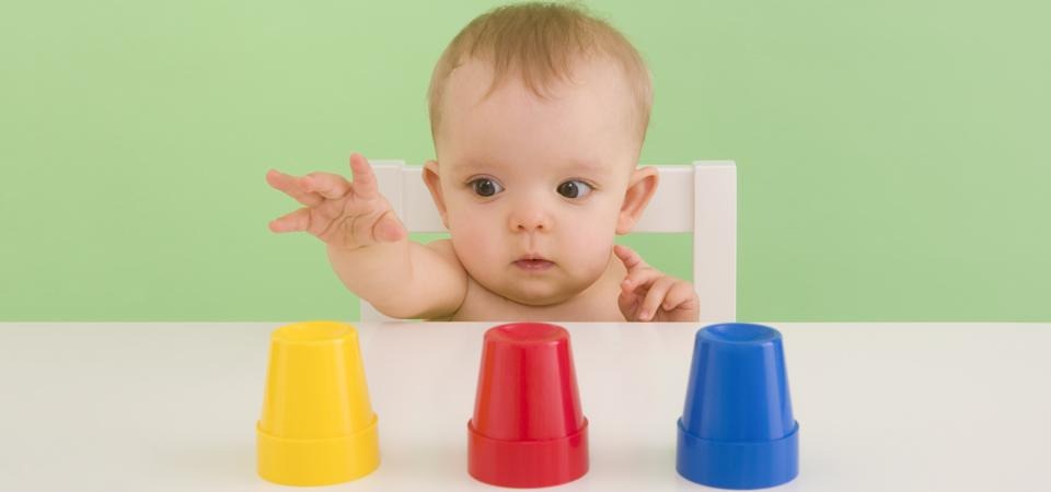 A baby choosing colourful cups